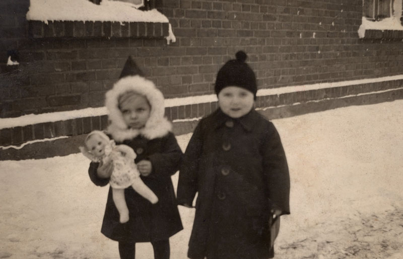 Sesutė Magdalena Klumbytė ir broliukas Vilius Klumbys prie savo namų Miškogalių (dabar Petrelių) kaime karo metais. Magdalena su savo mylima lėle, kurią baigiantis karui prarado.
