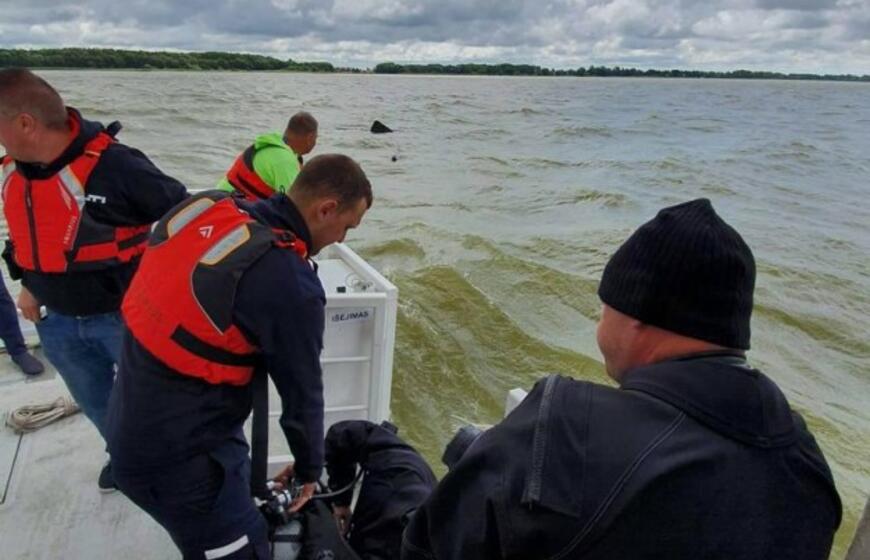 Į krantą traukiamas apvirtęs laivas kurėnas