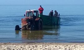 Apsipylęs tepalais traktorius važiuoja į jūrą