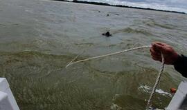 Į krantą traukiamas apvirtęs laivas kurėnas