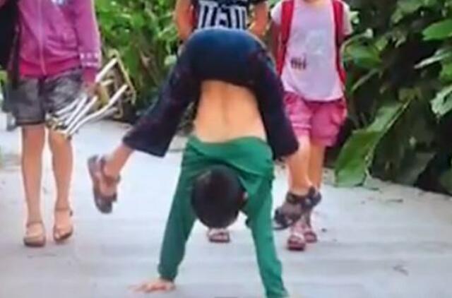 Paralyžiuotas berniukas į mokyklą keliauja eidamas rankomis